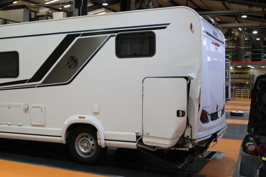 Wohnmobil mit geöffnetem seitlichem Staufach in einer Werkstatt