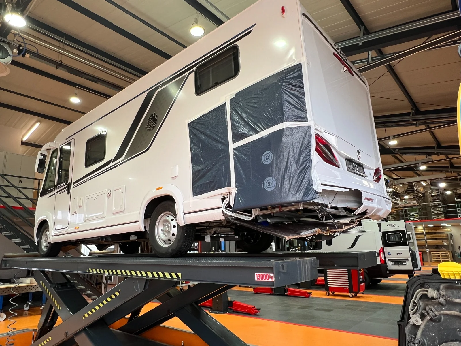 Wohnmobil auf einer Hebebühne mit geöffnetem Heckbereich